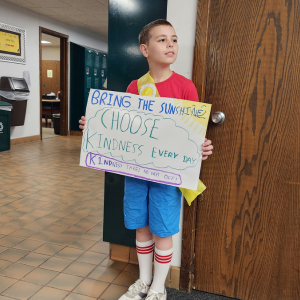 student standing in hallway holding a poster