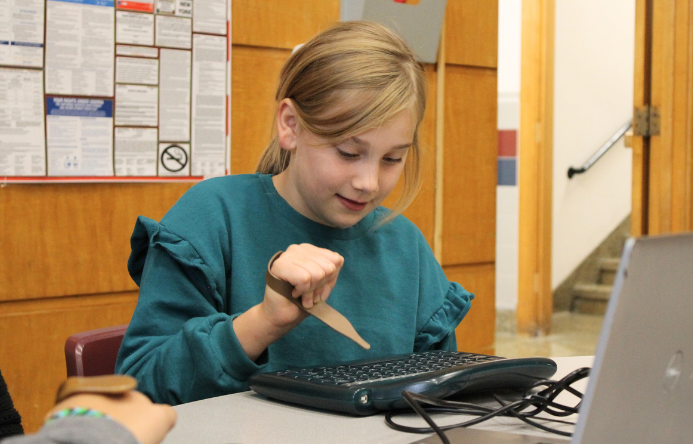 a student using a typing aid to type on a computer keyboard