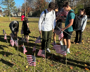 Members of Patriot Club outside of the high school placing flags in the lawn