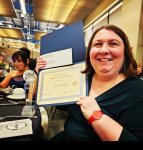 Dr. Denise Mahns holds up her New York State World Language Teacher of the Year Award at the 2024 NYSAFLT Conference.