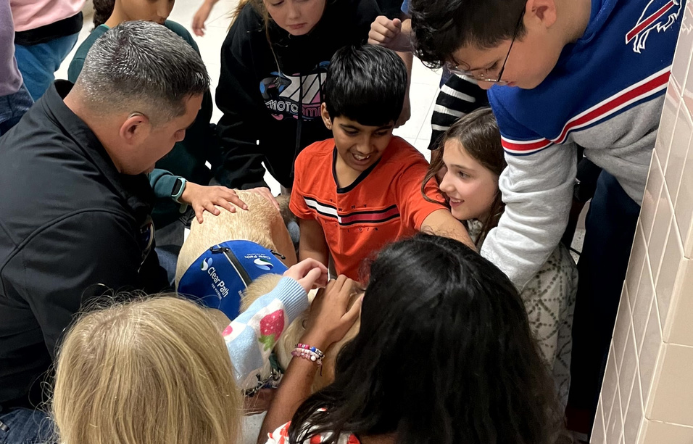 Students gathered on the floor petting a service dog in training