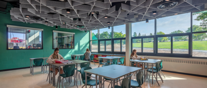 students sitting at tables in a modernized classroom which features a geometric ceiling design