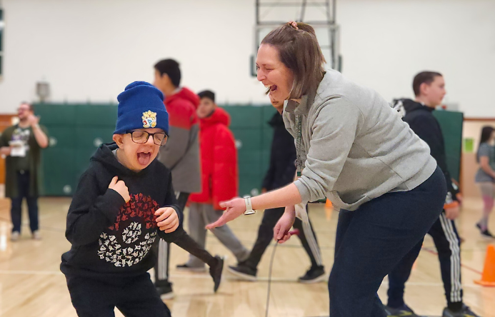 a student and teacher smiling in the gym as the teacher reaches for a high-five