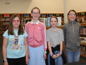 Four students standing the library and posing for a picture