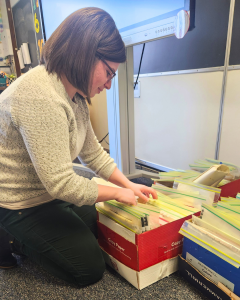 Meaghan Bedigian sitting on the floor, looking through boxes filled with time capsule bags